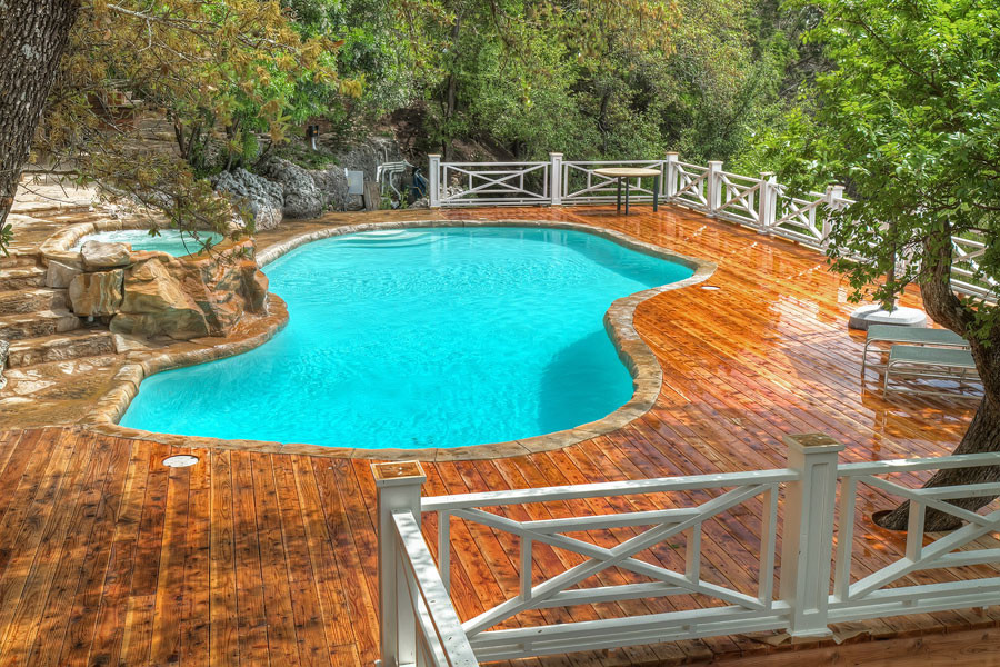 Cette image montre un grand couloir de nage arrière méditerranéen sur mesure avec un bain bouillonnant et une terrasse en bois.