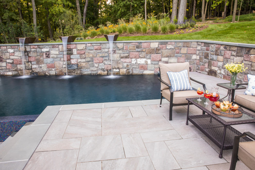 This is an example of a large contemporary back l-shaped above ground swimming pool in New York with tiled flooring.