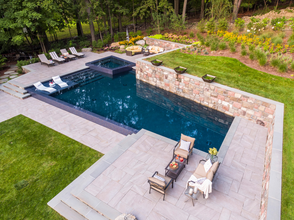 Modelo de piscina elevada contemporánea grande en forma de L en patio trasero con suelo de baldosas