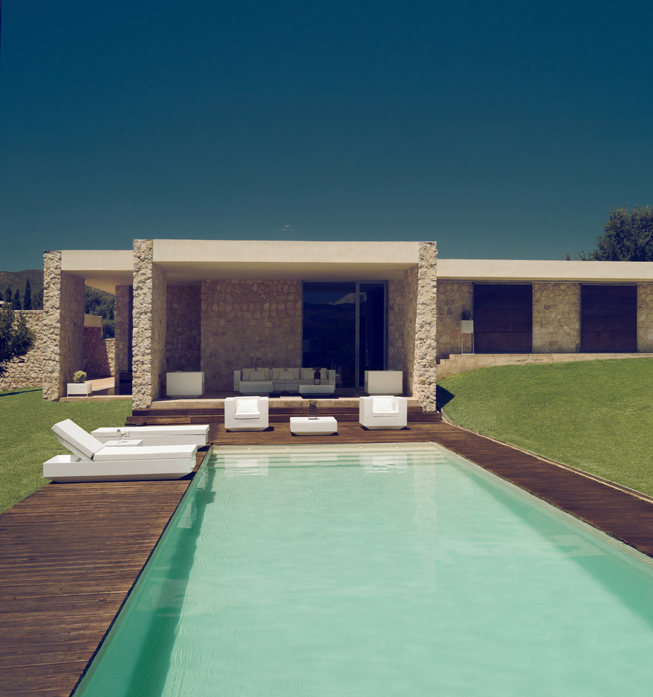 Immagine di una grande piscina a sfioro infinito moderna rettangolare dietro casa con pedane