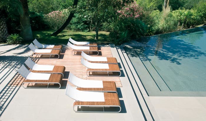 Immagine di un'ampia piscina a sfioro infinito design personalizzata dietro casa con pavimentazioni in cemento