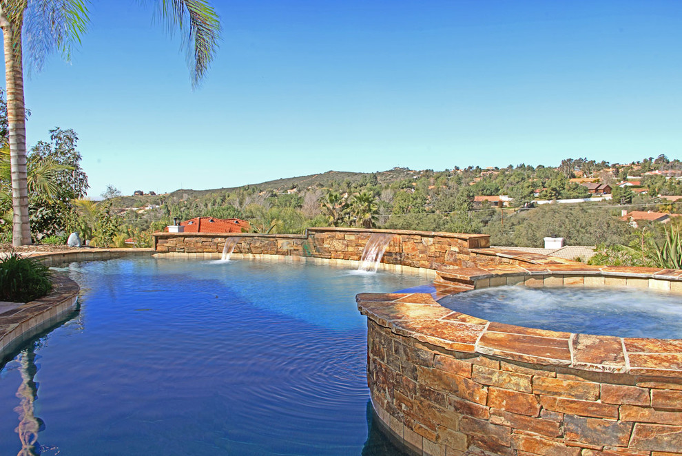 Photo of a large traditional back custom shaped swimming pool in San Diego with a water feature.