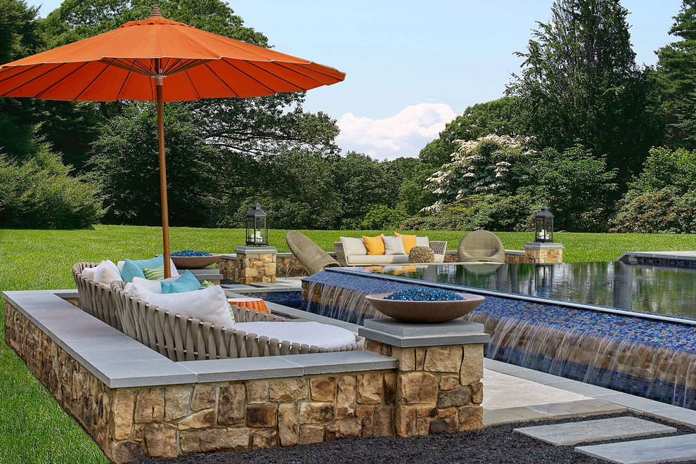 Cette image montre une grande piscine à débordement et arrière design rectangle avec des pavés en pierre naturelle.