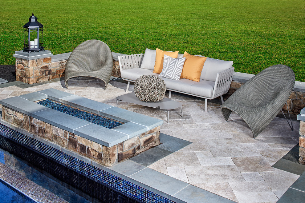 Modelo de piscina infinita moderna grande rectangular en patio trasero con adoquines de piedra natural