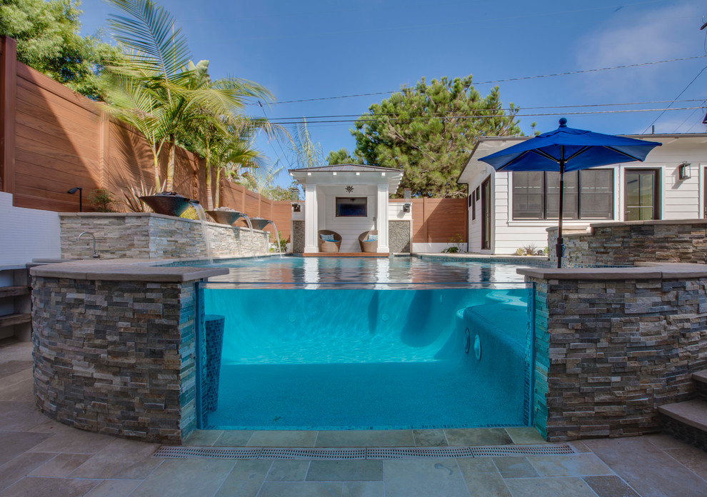 Diseño de piscina con fuente infinita tradicional grande a medida en patio trasero con adoquines de piedra natural