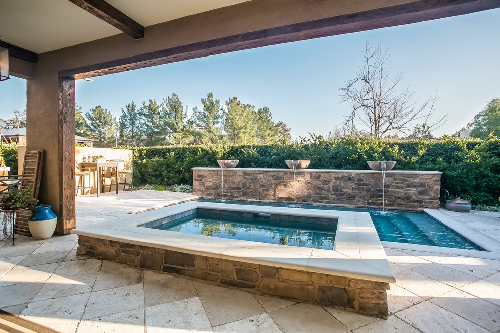 Ejemplo de piscina con fuente mediterránea pequeña rectangular en patio trasero con adoquines de piedra natural