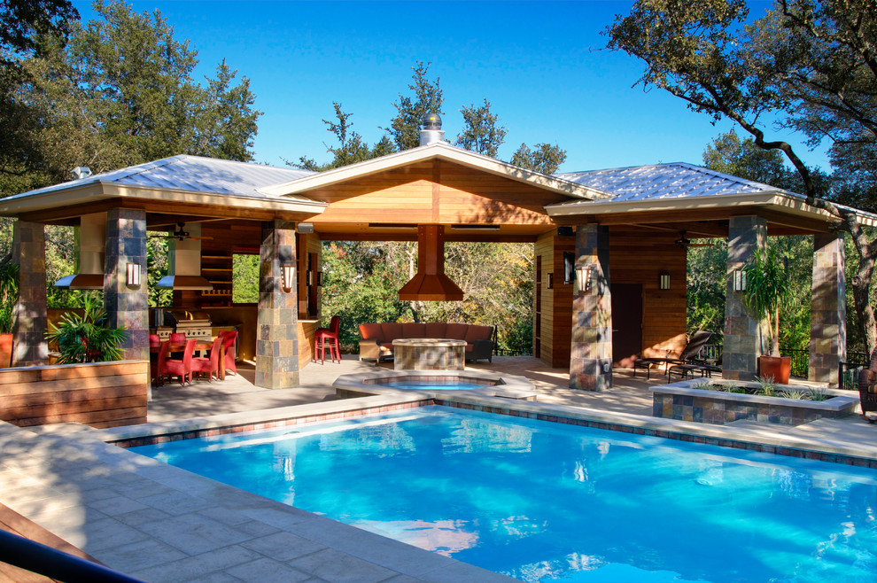 Modelo de piscinas y jacuzzis alargados tradicionales de tamaño medio rectangulares en patio trasero con adoquines de piedra natural