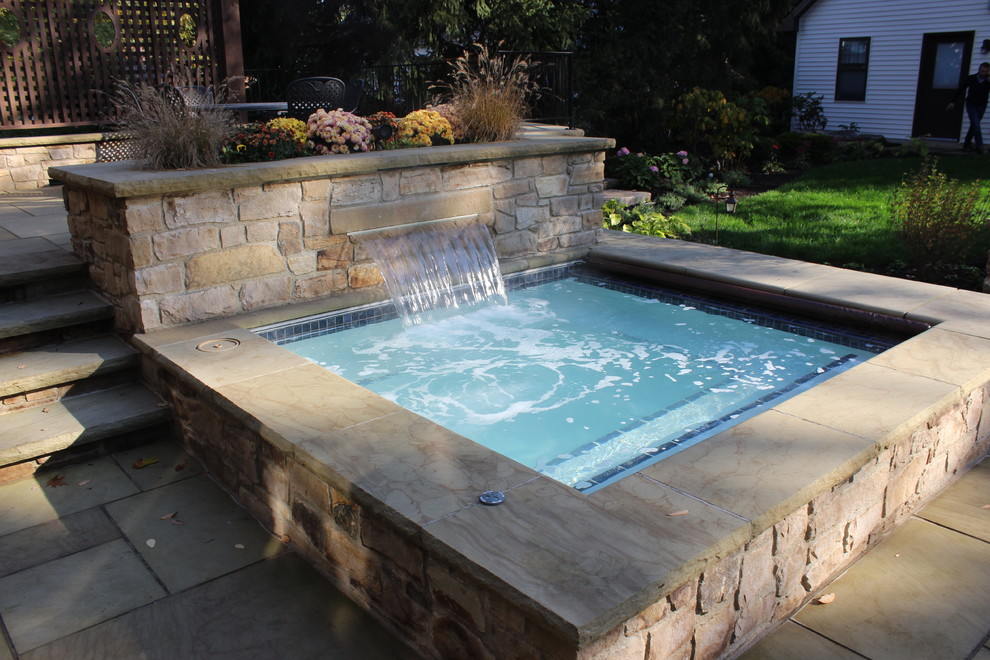 Ejemplo de piscinas y jacuzzis clásicos pequeños rectangulares en patio trasero con adoquines de hormigón
