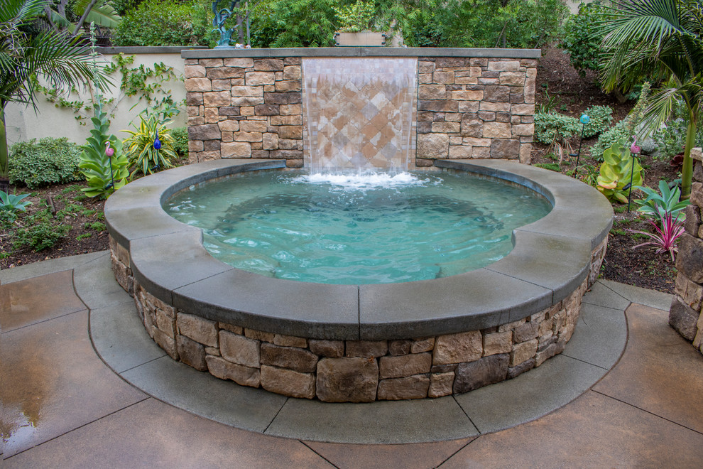 Large mediterranean back custom shaped hot tub in Orange County with concrete paving.