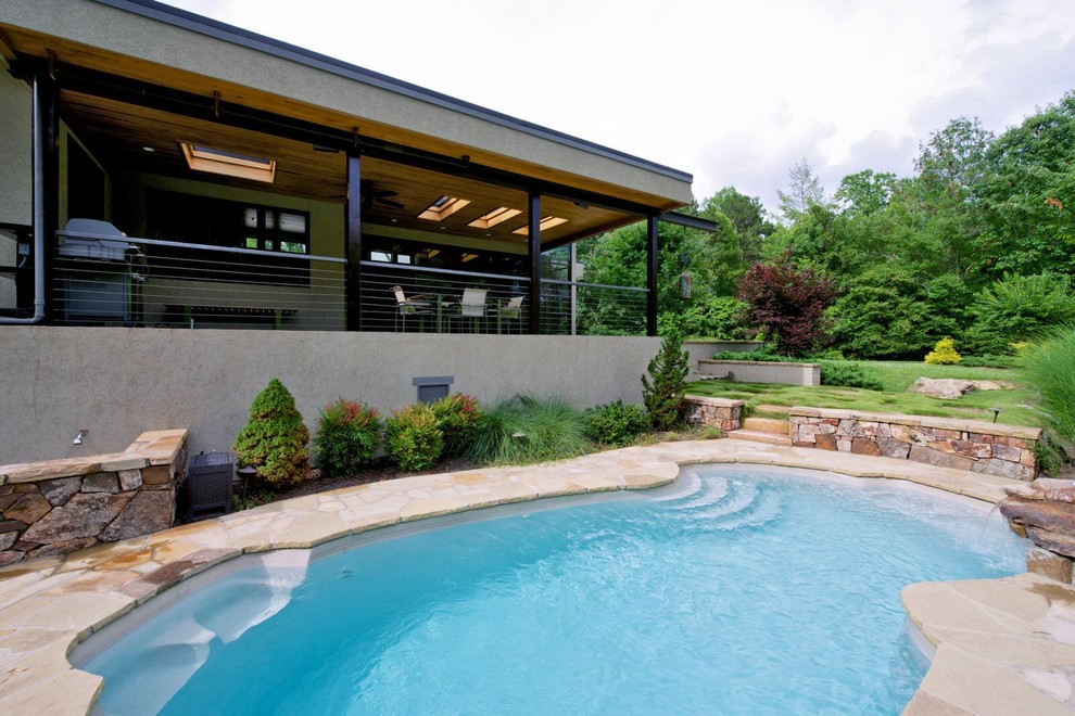 На фото: естественный бассейн среднего размера, в форме фасоли на заднем дворе в стиле модернизм с покрытием из каменной брусчатки и фонтаном с