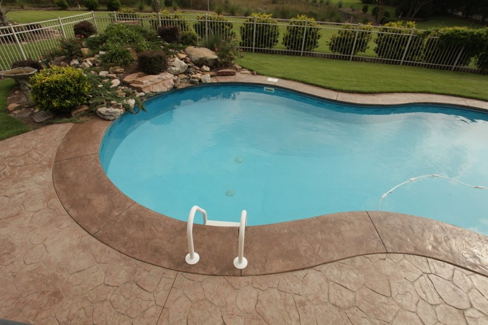 Imagen de piscina con fuente natural tradicional de tamaño medio redondeada en patio trasero con suelo de hormigón estampado