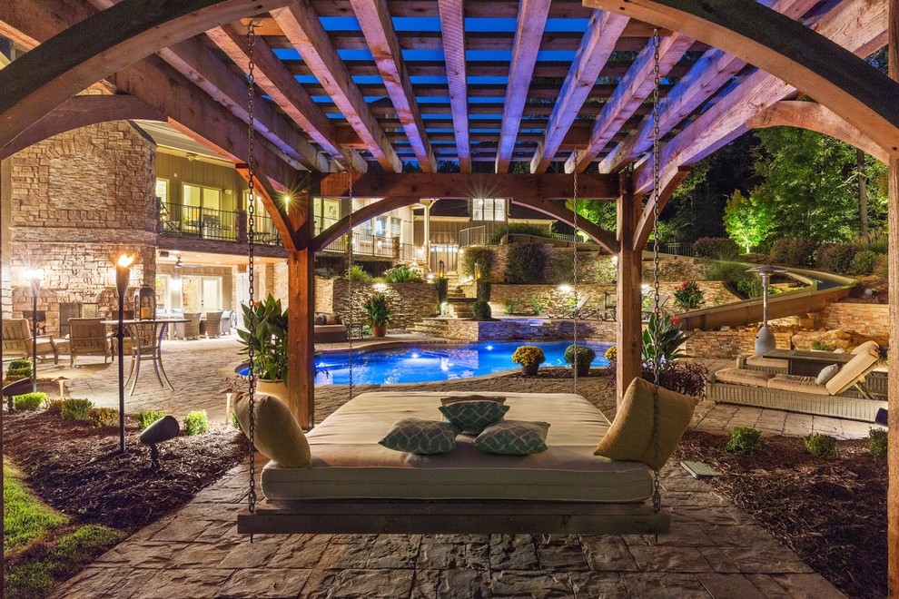 Bild på en mycket stor funkis anpassad pool på baksidan av huset, med vattenrutschkana och naturstensplattor