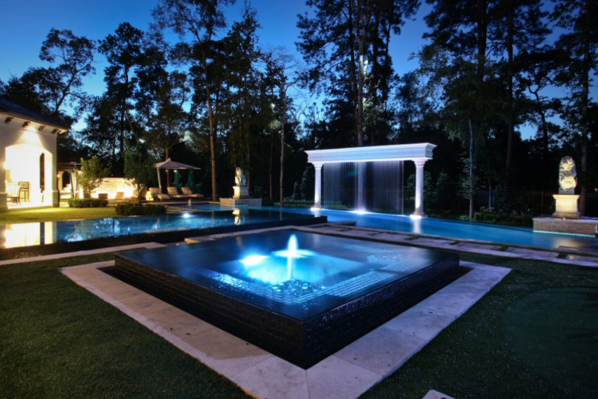 Ispirazione per un'ampia piscina a sfioro infinito tropicale personalizzata dietro casa con fontane e piastrelle