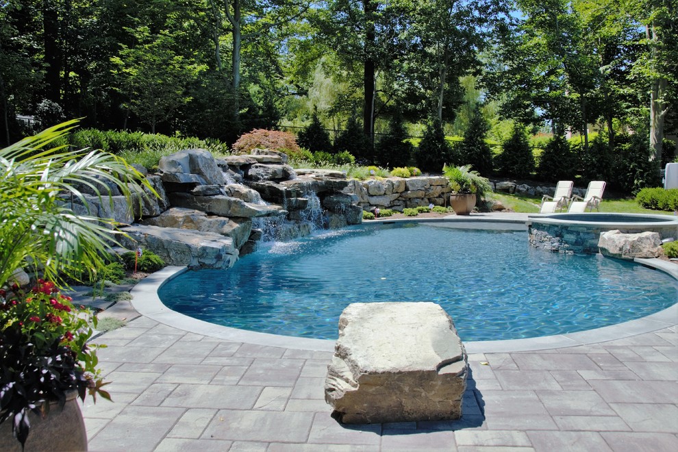 Ejemplo de piscinas y jacuzzis alargados exóticos grandes tipo riñón en patio trasero con adoquines de piedra natural