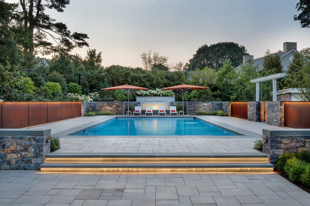 Modelo de piscina clásica renovada rectangular en patio trasero con adoquines de hormigón
