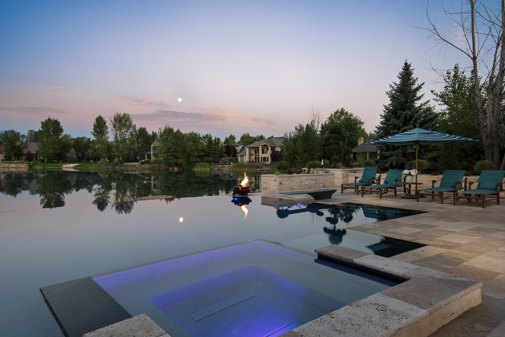 Immagine di una grande piscina a sfioro infinito mediterranea personalizzata dietro casa con una vasca idromassaggio e pavimentazioni in pietra naturale