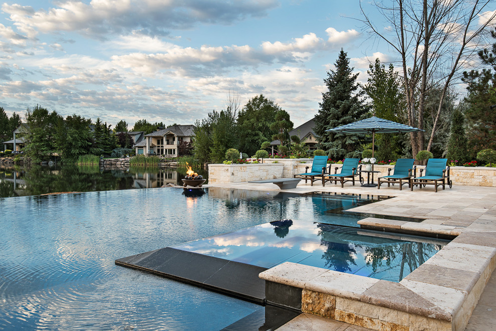 Esempio di una grande piscina a sfioro infinito mediterranea personalizzata dietro casa con una vasca idromassaggio e pavimentazioni in pietra naturale