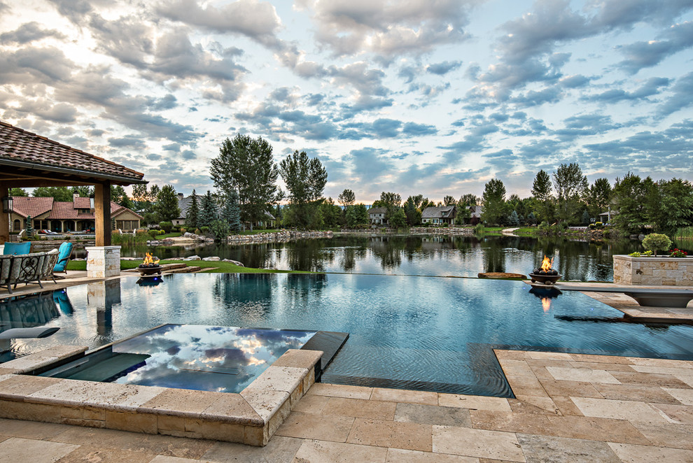 Ejemplo de piscinas y jacuzzis infinitos mediterráneos grandes a medida en patio trasero con adoquines de piedra natural