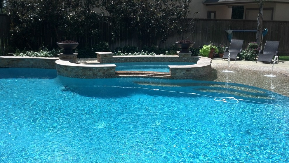Esempio di una piscina classica personalizzata dietro casa con una vasca idromassaggio e lastre di cemento