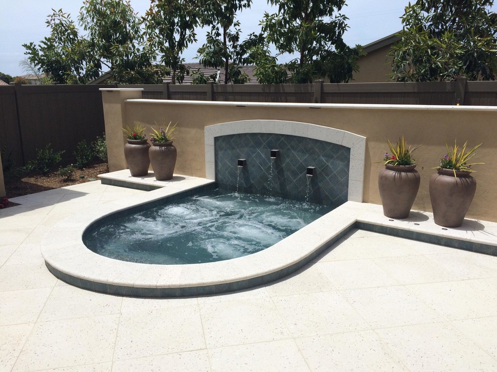 This is an example of a medium sized contemporary back rectangular swimming pool in San Diego with a water feature and concrete paving.