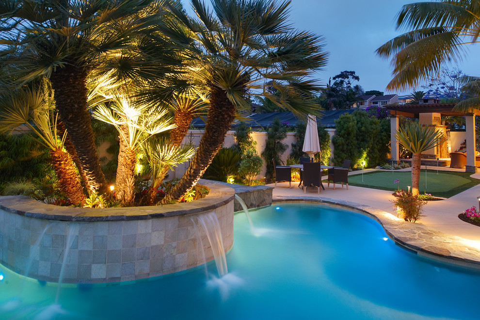 Imagen de piscina con fuente exótica grande a medida en patio trasero con adoquines de hormigón