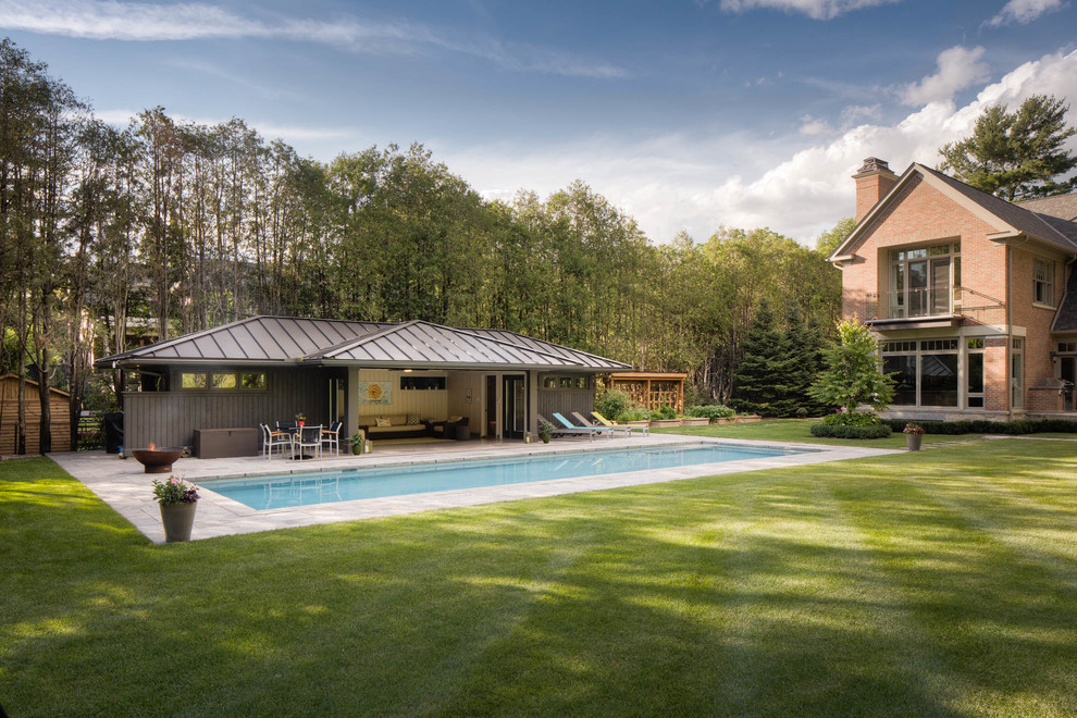 Пример оригинального дизайна: большой спортивный, прямоугольный бассейн на заднем дворе в стиле неоклассика (современная классика) с домиком у бассейна и покрытием из каменной брусчатки