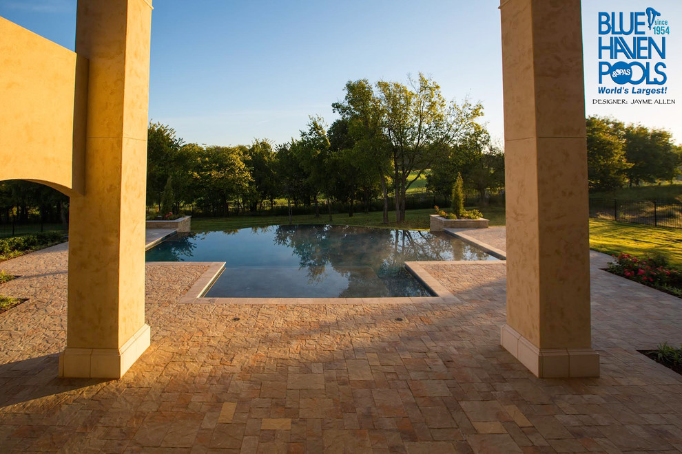 Immagine di una grande piscina a sfioro infinito contemporanea personalizzata dietro casa con fontane e pavimentazioni in cemento