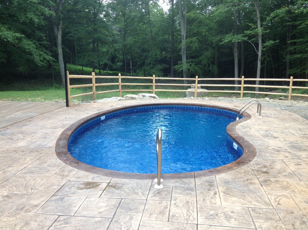 Imagen de piscina pequeña tipo riñón en patio lateral con suelo de hormigón estampado