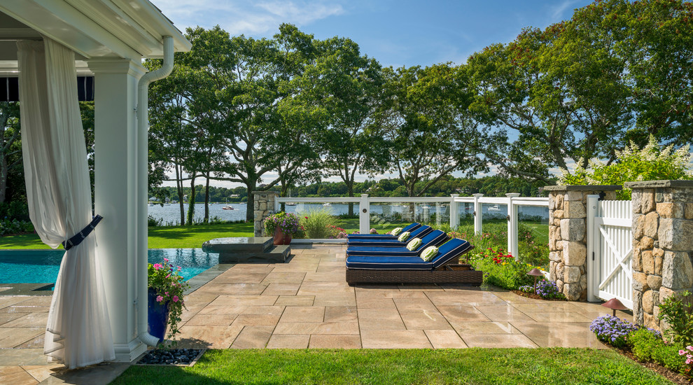 Design ideas for a large beach style back swimming pool in Boston with natural stone paving.
