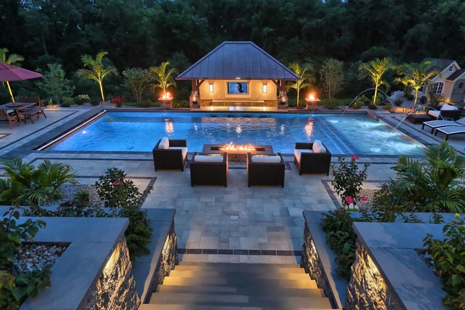 Foto de piscina con fuente exótica grande rectangular en patio trasero con adoquines de piedra natural