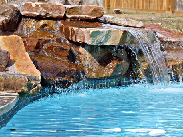 Ispirazione per una grande piscina monocorsia design personalizzata dietro casa con una vasca idromassaggio e pavimentazioni in cemento