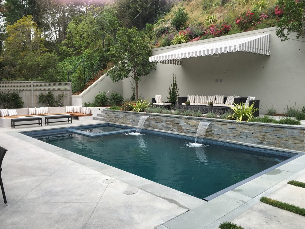 Modelo de piscina alargada clásica renovada de tamaño medio rectangular en patio trasero con suelo de baldosas