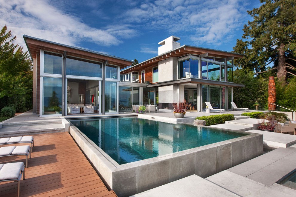 Ispirazione per un'ampia piscina fuori terra design rettangolare dietro casa con lastre di cemento
