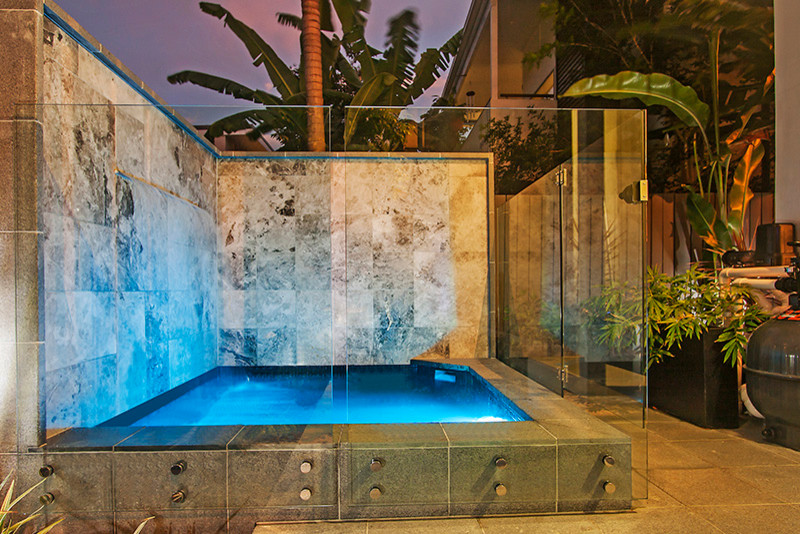 Photo of a small contemporary courtyard custom shaped swimming pool in Brisbane with a water feature and tiled flooring.