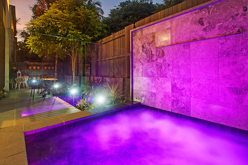 Small contemporary courtyard custom shaped swimming pool in Brisbane with a water feature and tiled flooring.