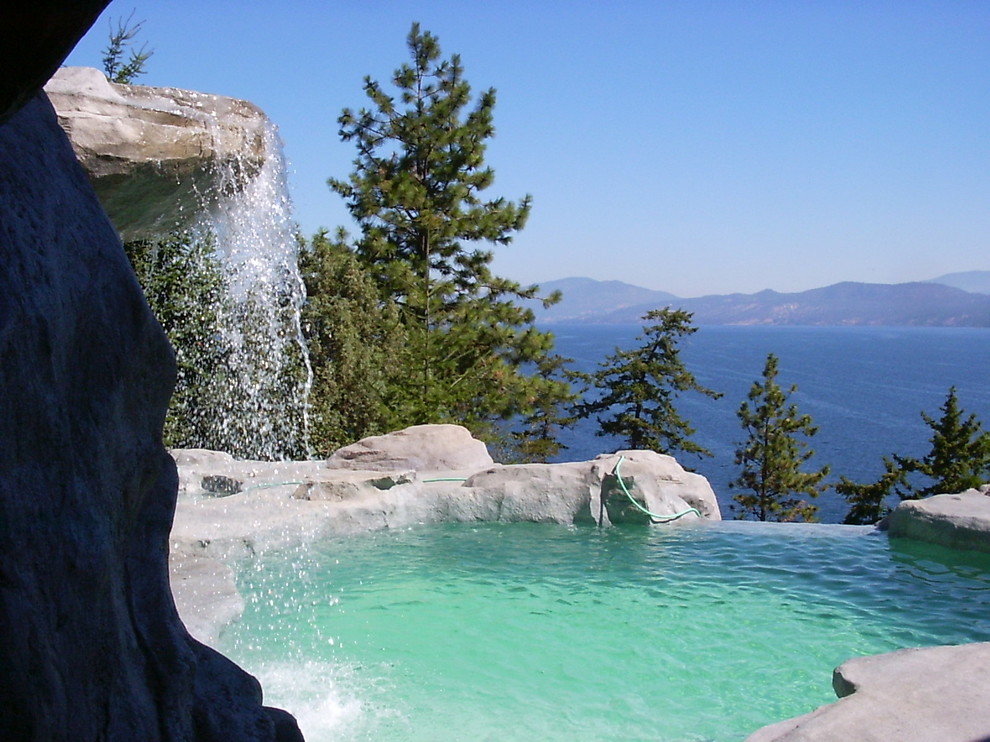 Immagine di una piscina naturale rustica personalizzata dietro casa con fontane e pavimentazioni in pietra naturale