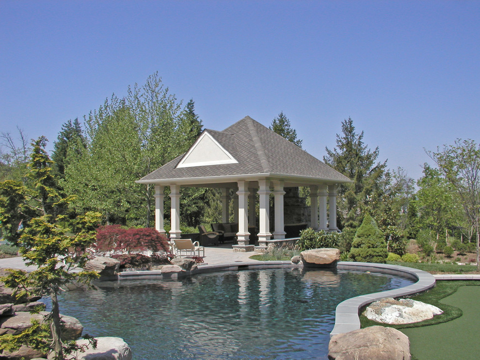 Идея дизайна: огромный естественный бассейн произвольной формы на заднем дворе в современном стиле с домиком у бассейна и мощением тротуарной плиткой
