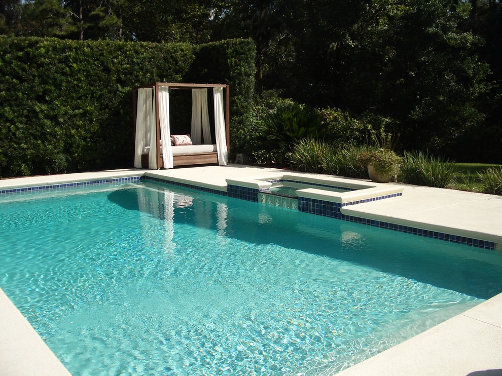 Bild på en mellanstor funkis rektangulär pool, med betongplatta