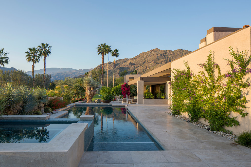 Foto di una grande piscina minimal rettangolare dietro casa con una vasca idromassaggio e pavimentazioni in pietra naturale