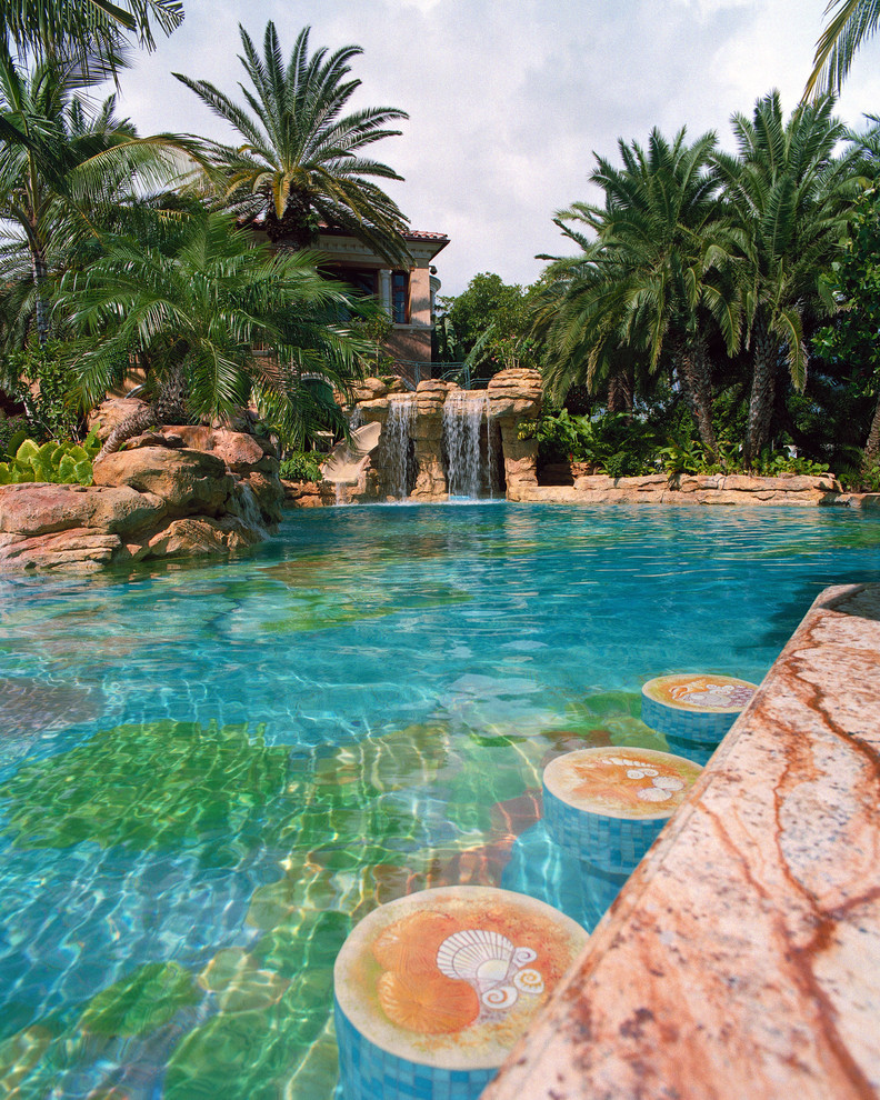 Geräumiger Mediterraner Infinity-Pool hinter dem Haus in individueller Form mit Natursteinplatten in Miami
