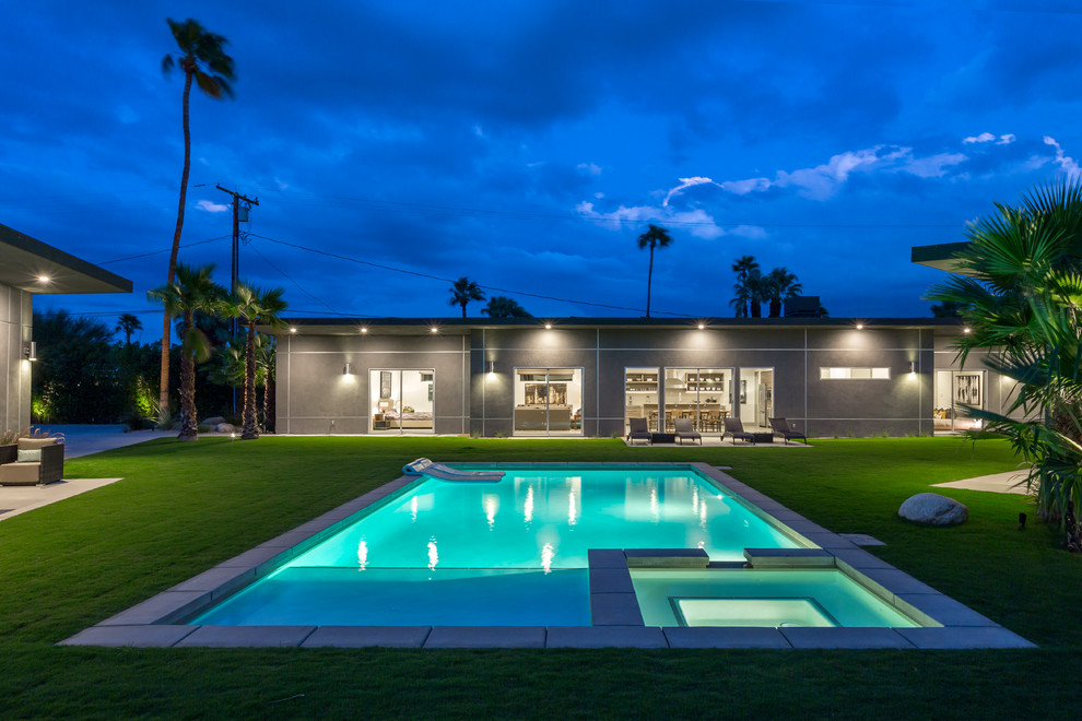 Foto di una grande piscina monocorsia design rettangolare dietro casa con una vasca idromassaggio e pavimentazioni in pietra naturale