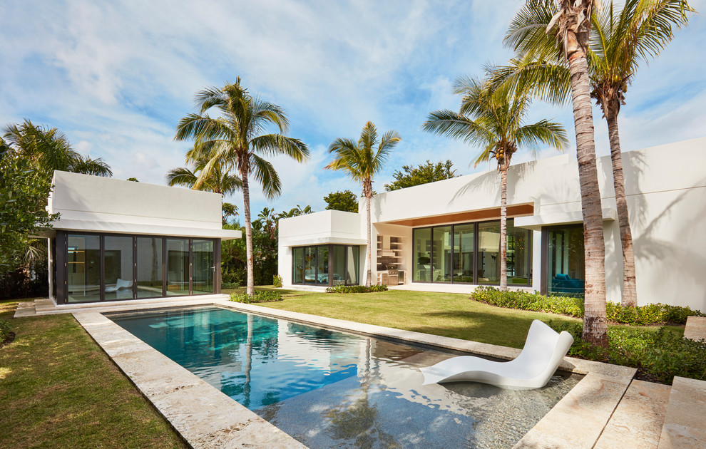 This is an example of a contemporary back rectangular lengths swimming pool in Miami with tiled flooring.