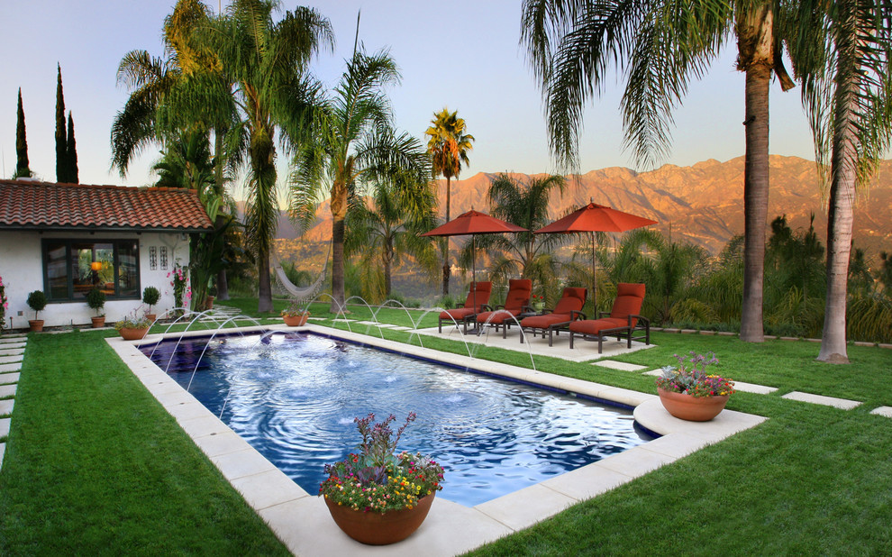 Diseño de piscina con fuente alargada mediterránea de tamaño medio a medida en patio trasero con losas de hormigón