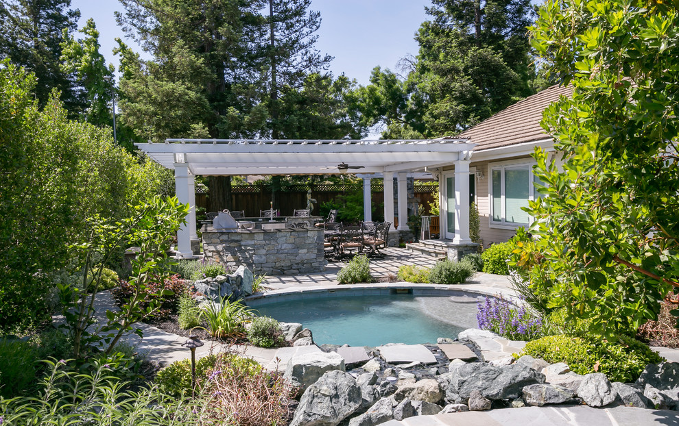 Foto de piscina con fuente natural exótica pequeña redondeada en patio trasero con adoquines de piedra natural