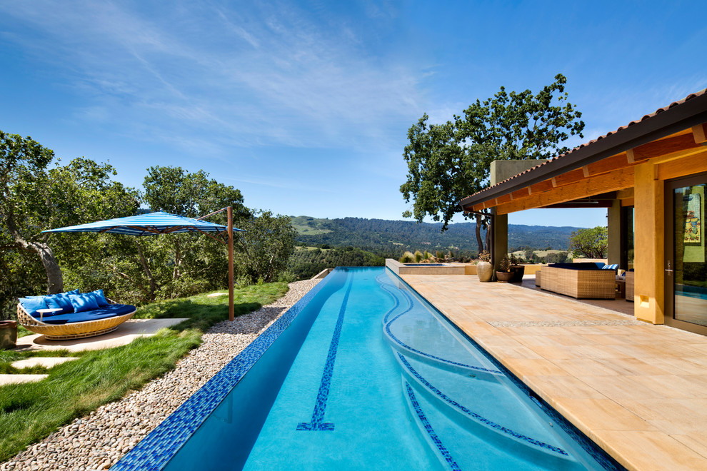 Immagine di una grande piscina monocorsia american style rettangolare dietro casa con una vasca idromassaggio e piastrelle