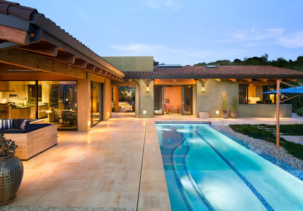 Modelo de piscina alargada de estilo americano grande rectangular en patio trasero con suelo de baldosas