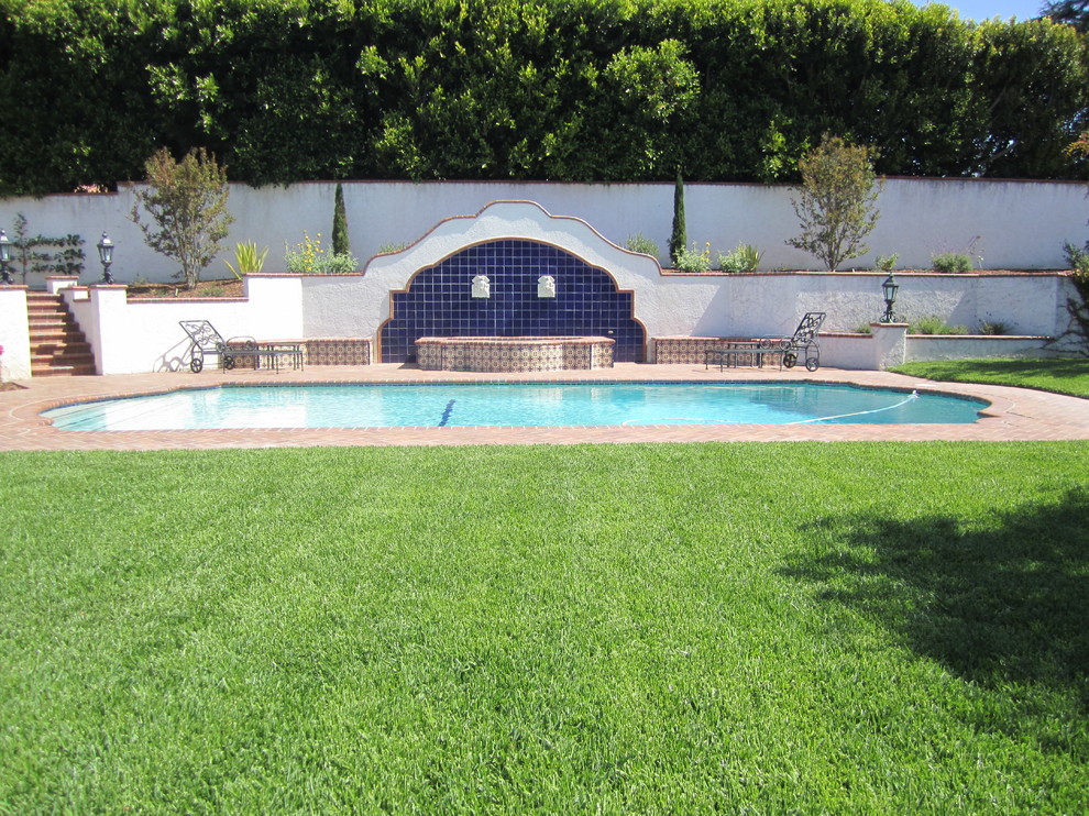 Imagen de piscina alargada mediterránea grande a medida en patio trasero con adoquines de ladrillo