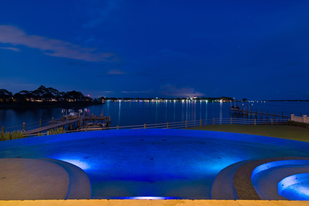 Modelo de piscina con fuente infinita mediterránea grande en patio trasero con adoquines de ladrillo