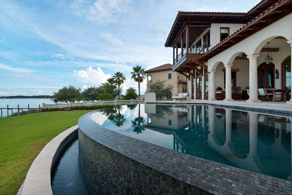Пример оригинального дизайна: большой бассейн-инфинити на заднем дворе в средиземноморском стиле с фонтаном и мощением клинкерной брусчаткой