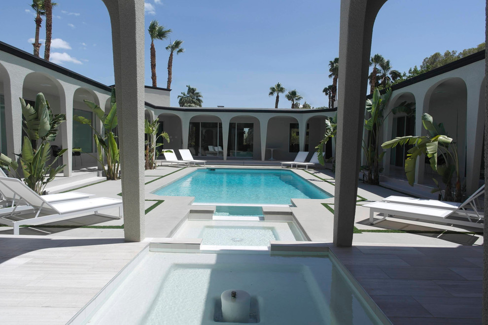 Ispirazione per un'ampia piscina moderna rettangolare in cortile con pavimentazioni in pietra naturale e una vasca idromassaggio